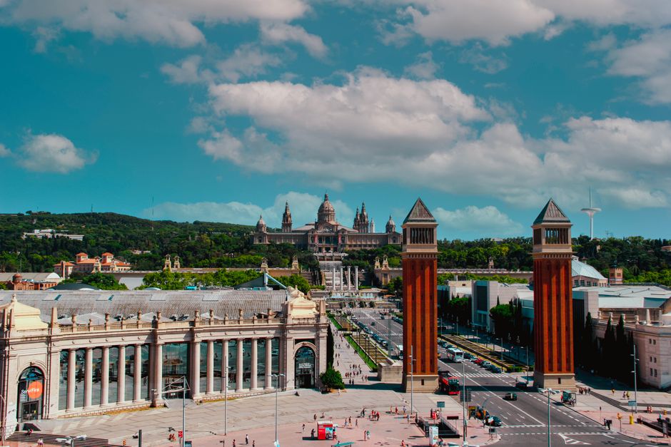 Una impresionante toma aérea de la Plaça Espanya de Barcelona con monumentos icónicos y la vibrante vida de la ciudad.
