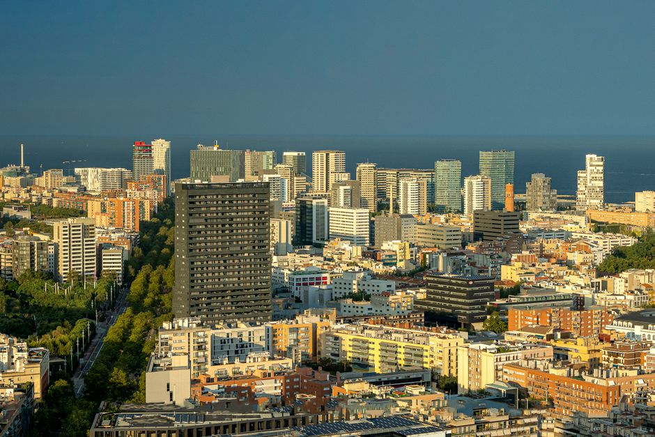 Vista aérea del moderno horizonte de Barcelona encontrándose con el Mar Mediterráneo al atardecer.