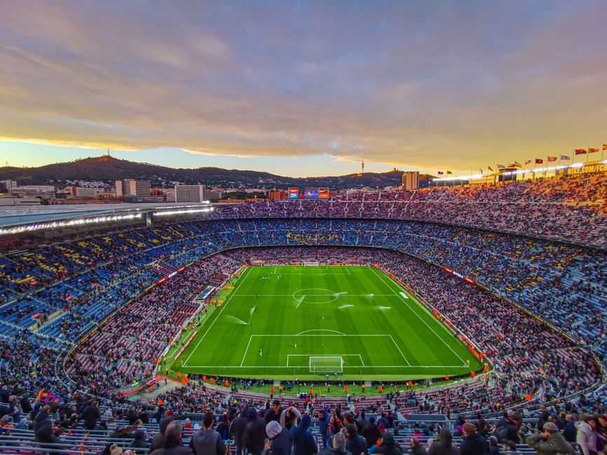 Vista aérea del estadio Camp Nou lleno de espectadores durante un partido de fútbol al atardecer en Barcelona, España.