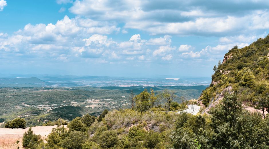 Vista escénica de Montserrat, España, con paisajes exuberantes bajo un cielo vibrante.