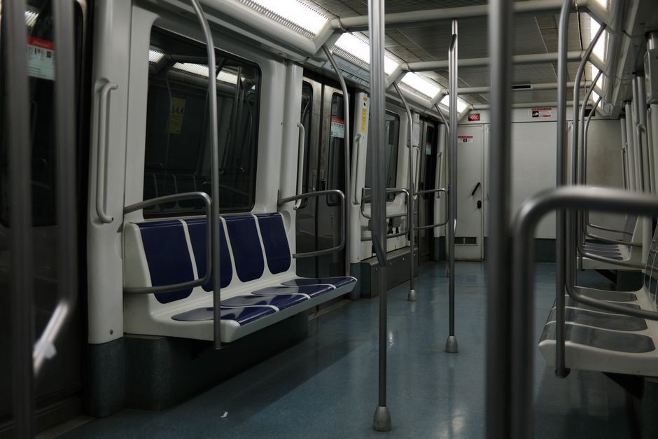 Un interior de vagón de metro tranquilo con asientos azules y postes de metal, capturado con luz suave.