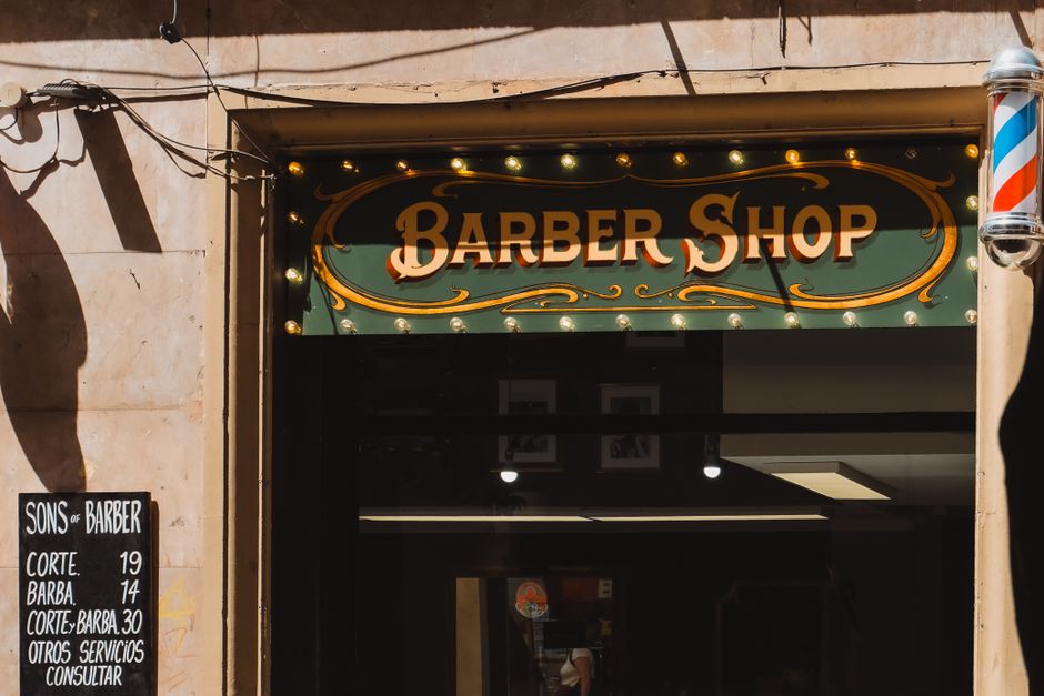Una entrada de barbería de estilo vintage en Barcelona, con letreros y decoración clásicos.