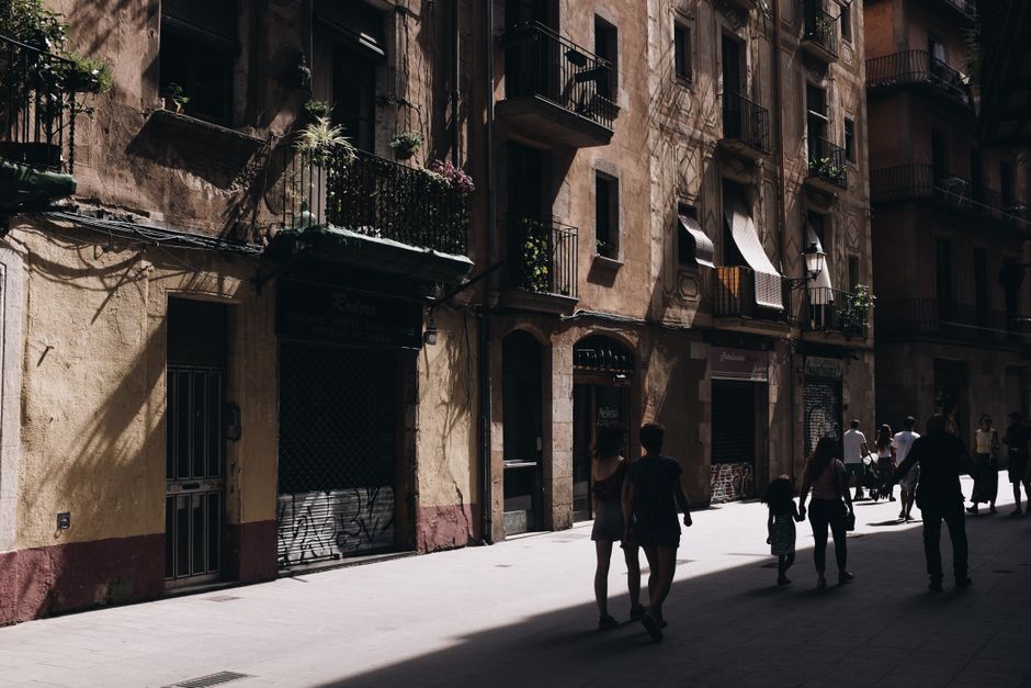 Una calle urbana bulliciosa en Barcelona con arquitectura histórica y juego de sombras en las fachadas.