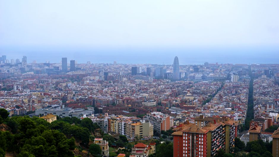 Una impresionante vista aérea del paisaje urbano de Barcelona con el horizonte y el mar Mediterráneo al fondo.
