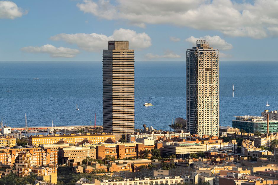 Vista aérea del horizonte de Barcelona con rascacielos icónicos y el Mar Mediterráneo.