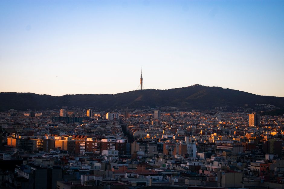 Un paisaje urbano de Barcelona con la icónica Torre Collserola contra un cielo al amanecer.