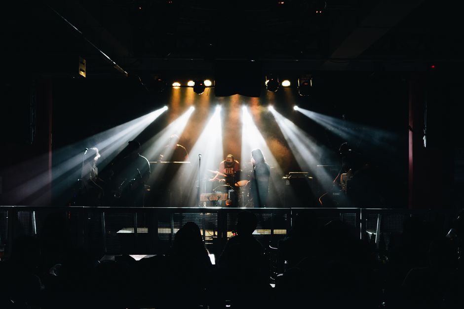 Un vibrante concierto de música en vivo en Lima, Perú, con músicos en el escenario y una iluminación dramática.