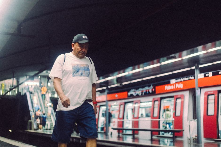 Un hombre camina casualmente en una estación de metro moderna vistiendo ropa informal.