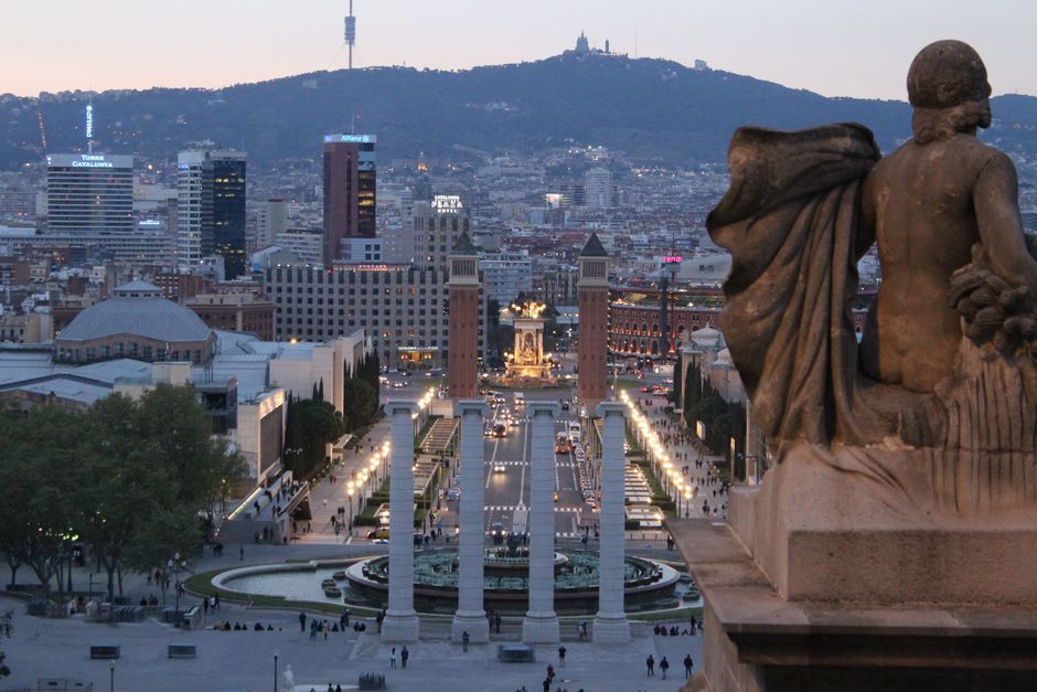 Admira el impresionante paisaje urbano de Barcelona desde la colina de Montjuïc al atardecer, mostrando la arquitectura icónica y la vida vibrante de la ciudad.