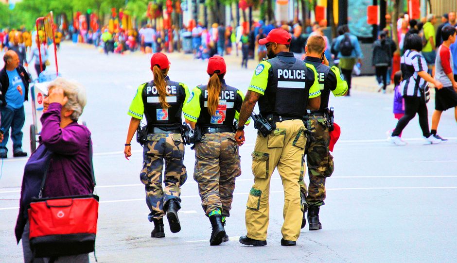 Grupo de policías uniformados patrullando una calle concurrida de la ciudad en un día soleado.