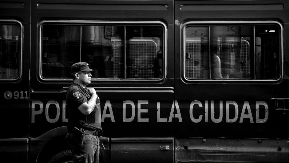 Fotografía en blanco y negro de un oficial de policía de la ciudad junto a un vehículo en Buenos Aires.