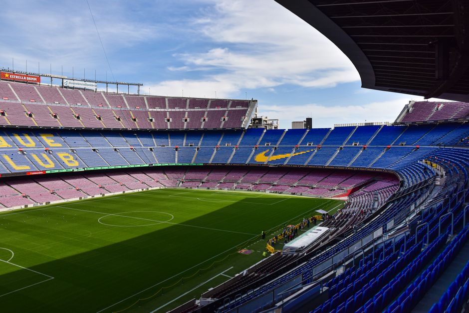 Amplia vista del icónico estadio Camp Nou en Barcelona, mostrando sus vastas gradas vacías y su campo verde.