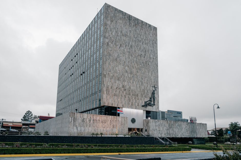 Fotografía arquitectónica del edificio de la Corte Suprema en San José, Costa Rica, que destaca por su diseño moderno y las banderas nacionales.