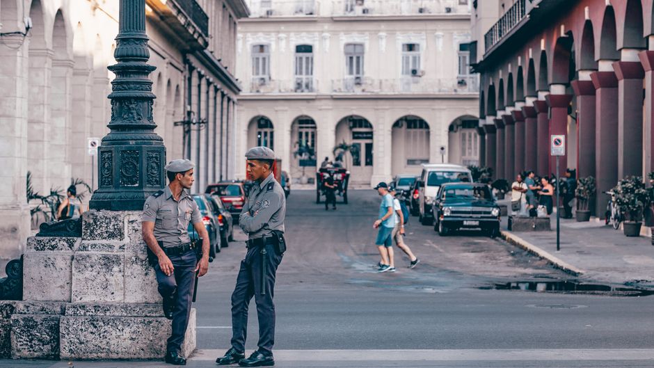 Oficiales de policía conversando en una pintoresca calle de La Habana, mostrando la arquitectura histórica.