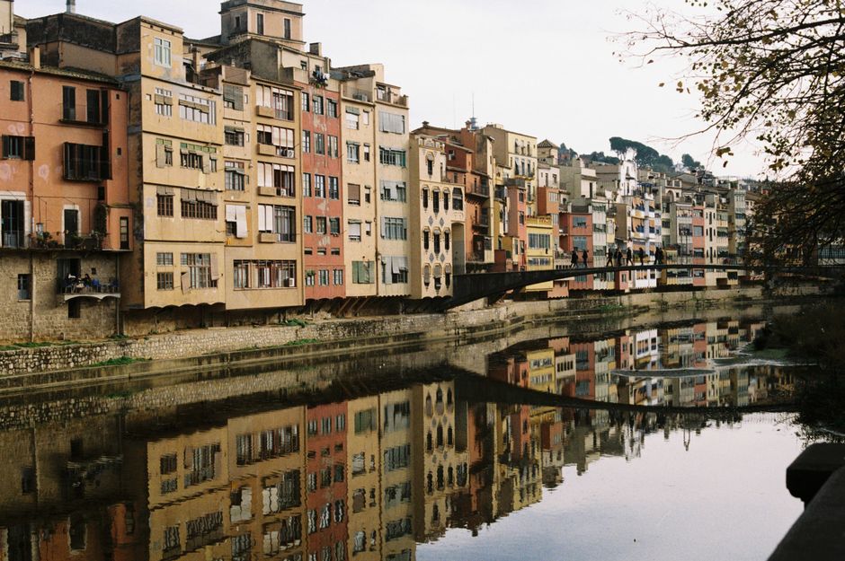 Edificios históricos vibrantes reflejándose en el río en Girona, Cataluña.