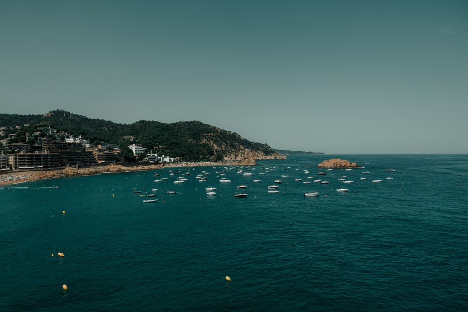 Una vista pintoresca de botes salpicando las aguas costeras de Tossa de Mar, España, en un claro día de verano.