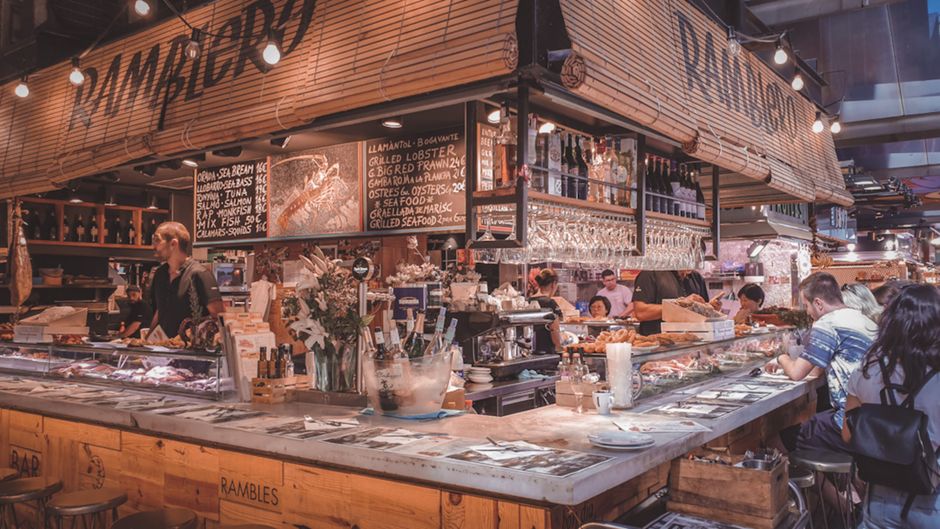 Puesto de comida animado en el mercado de Barcelona, capturando la vibrante atmósfera culinaria.
