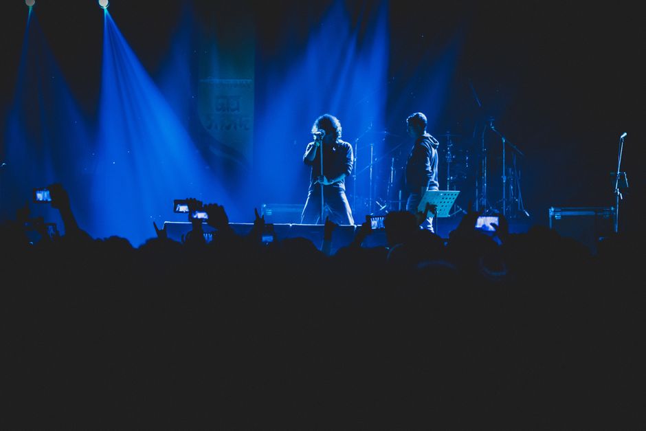 Una escena de concierto animada con luces vívidas, que presenta a un cantante y una banda en el escenario.
