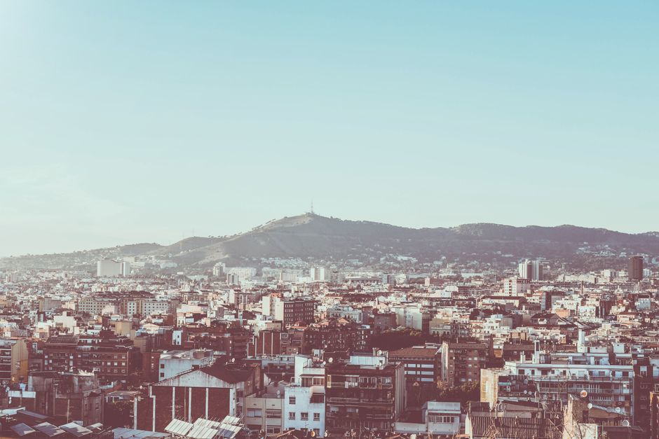 Una vista panorámica del paisaje urbano de Barcelona con Montjuïc al fondo bajo cielos despejados.