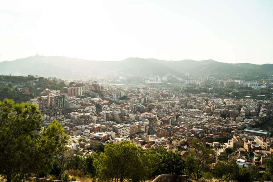 Vista aérea que captura el paisaje urbano de Barcelona rodeado de montañas y colinas durante el día.
