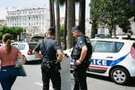 Los agentes de policía y un civil interactúan cerca de un coche patrullero en una concurrida calle de la ciudad.