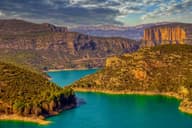Una impresionante vista aérea del vibrante paisaje en Camarasa, España, que presenta aguas claras y formaciones rocosas.