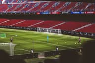 Práctica de fútbol en un famoso estadio con asientos rojos vibrantes y campo verde.