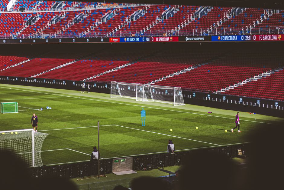 Práctica de fútbol en un famoso estadio con asientos rojos vibrantes y campo verde.