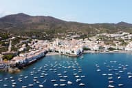 Impresionante vista aérea del encantador pueblo costero de Cadaqués con veleros y un puerto bullicioso durante el verano.