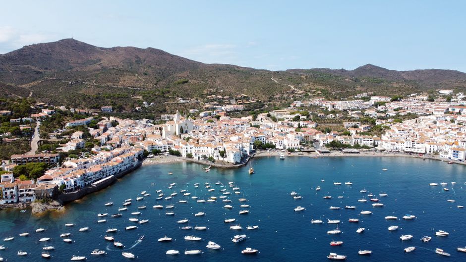 Impresionante vista aérea del encantador pueblo costero de Cadaqués con veleros y un puerto bullicioso durante el verano.