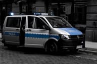 Una furgoneta de policía estacionada en una calle de adoquines en un entorno urbano.