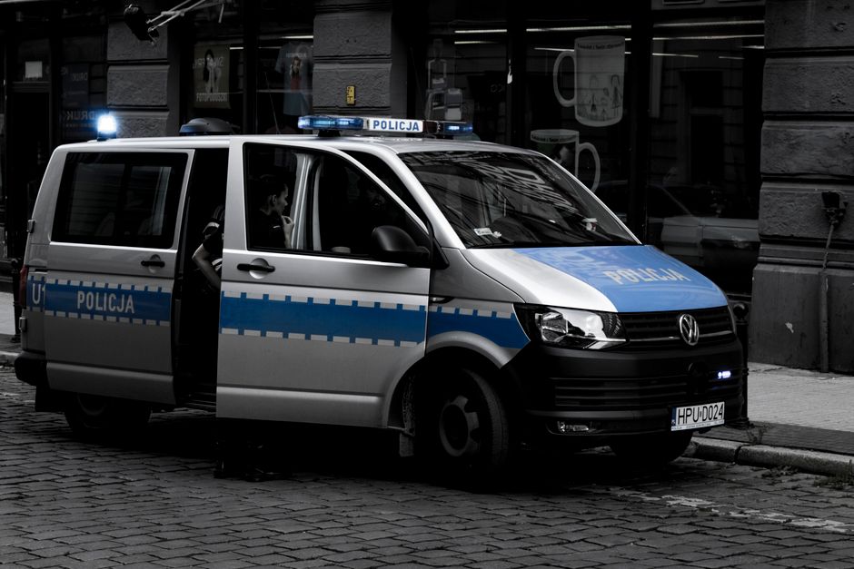 Una furgoneta de policía estacionada en una calle de adoquines en un entorno urbano.
