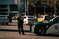 Policía en uniforme multando un coche en un entorno urbano de la Ciudad de México.