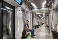 Vista interior de un tren de metro moderno con personas sentadas, mostrando el transporte urbano.