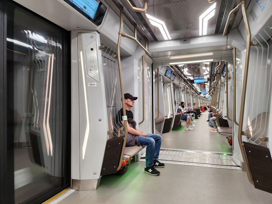 Vista interior de un tren de metro moderno con personas sentadas, mostrando el transporte urbano.